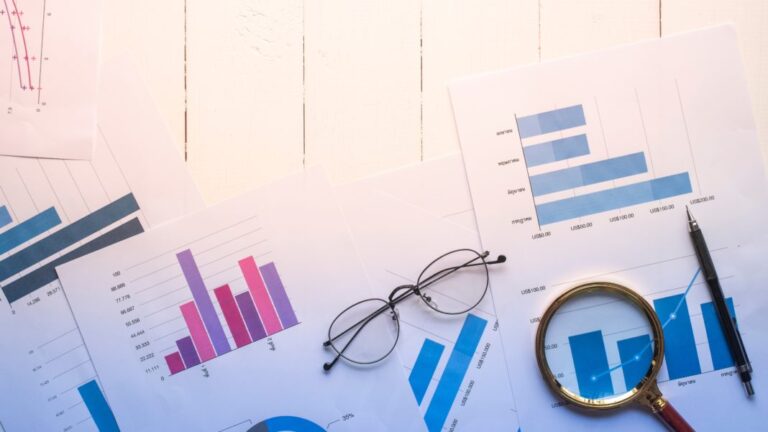 magnifying glass and documents with analytics data lying on table,selective focus