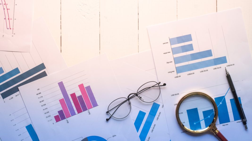 magnifying glass and documents with analytics data lying on table,selective focus