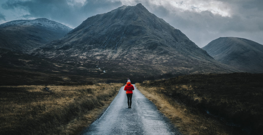 woman walking on a road in glen etive, scotland